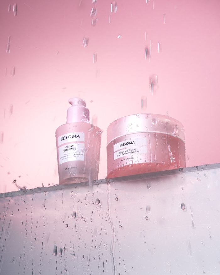 Beautiful skincare products photographed with water droplets on a pink background.