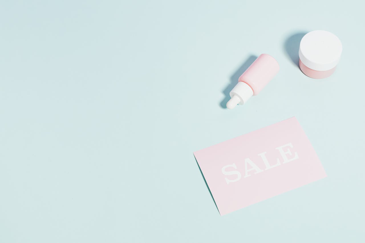 about-img Pink beauty products and sale sign on pastel backdrop.