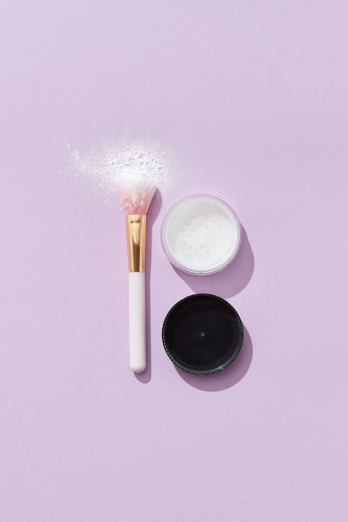 portfolio-img-01 A minimalistic flat lay of a makeup brush with loose powder set against a pastel purple backdrop.