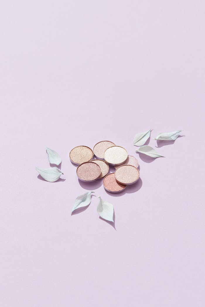 our-services-01 A flat lay of pastel eyeshadows surrounded by delicate petals on a soft pink background.