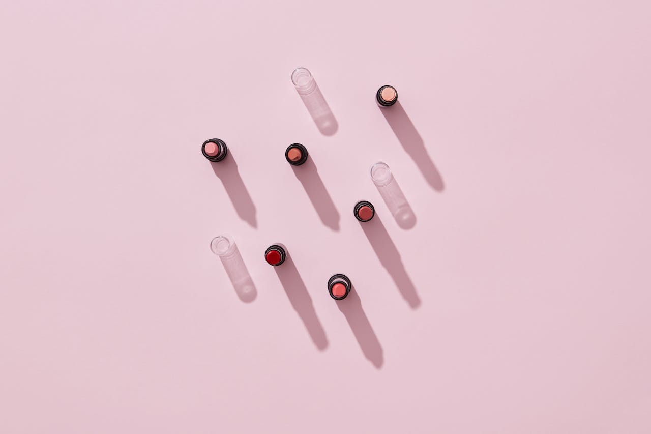 portfolio-img-02 Stylish flatlay of various lipstick shades casting shadows on a pink surface.